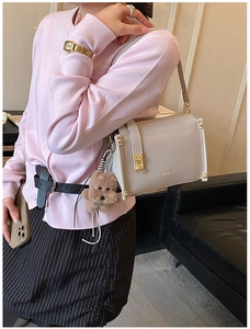 Detail of premium box bag with gold clasp and cute plush bear charm on soft leather