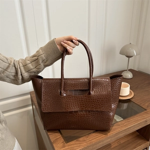 Brown crocodile embossed tote bag with large capacity in an elegant indoor setting