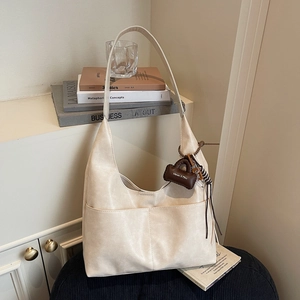 Minimalist beige PU leather hobo tote bag with dual front pockets and mini charm