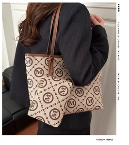 Detail of beige canvas tote bag with brown M logo pattern and matching clutch bag