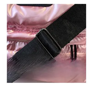 Détail de la bandoulière réglable avec boucle en métal sur le sac de voyage rose matelassé