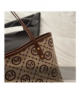 Close-up of brown monogram tote bag with leather trim and gold rivet details