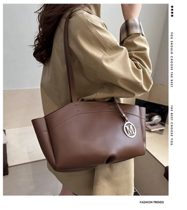 Detail of coffee brown leather handbag with pleated sides and metallic M letter charm