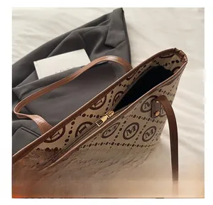 Close-up of smooth metal zipper and monogram canvas texture on luxury tote bag