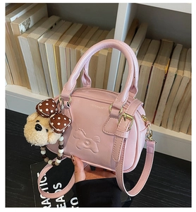 Detail of pink mini Boston bag featuring embossed pony motif and plush bear charm