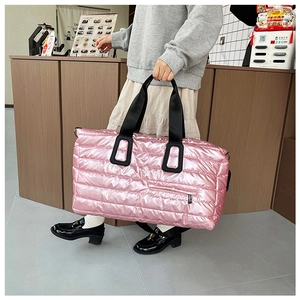 Sac de voyage matelassé rose avec finition brillante et poignées noires porté