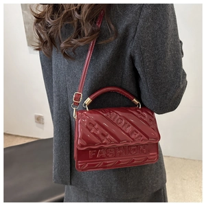 Detail van bordeauxrode lakslederen tas met ruitstiksel en FASHION-reliëf