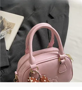 Detail of pink faux leather handbag with golden zipper and polka dot bow accessory