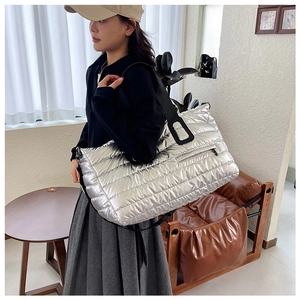 Détail du sac fourre-tout argenté matelassé avec poche zippée et bandoulière en nylon noir