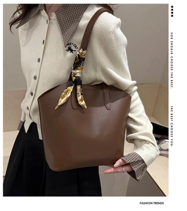 Detail of dark brown leather tote bag with elegant silk scarf wrapped on the handle
