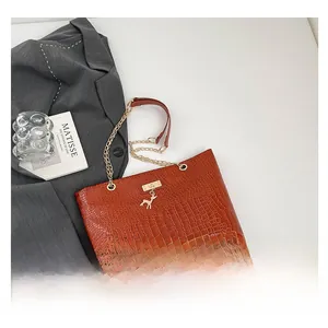 Brown crocodile embossed tote bag with gold deer charm and chain shoulder strap detail