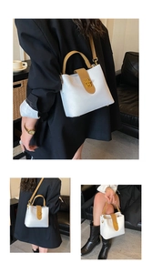 Detail showing the white bucket bag with brown handles and a gold twist lock closure