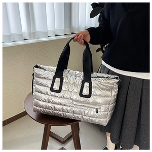 Gros plan du sac cabas matelassé argenté avec tissu métallique et poche zippée à l'avant