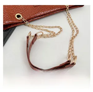 Detailed macro view of dark brown crocodile texture bag with gold chain strap details