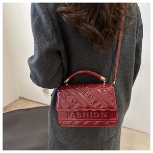 Detail van rode laklederen handtas met gewatteerd sterpatroon en fashion reliëf