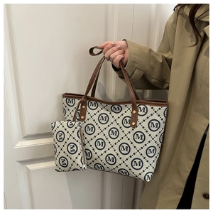 Detail view of canvas tote bag with M letter pattern, leather trim and matching pouch