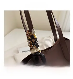 Detail shot of brown leather handbag handle wrapped with elegant printed silk scarf