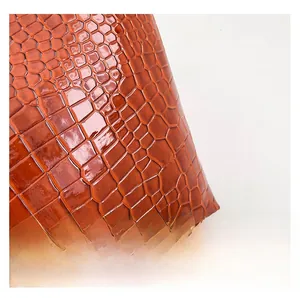 Detailed close-up showing the glossy brown crocodile embossed leather texture of the bag