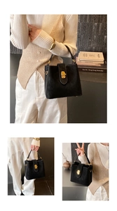 Detail of black suede bucket bag featuring a gold twist-lock and minimalist metal rings