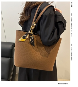 Detailed view of suede leopard print tote bag with decorative silk scarf on the handle