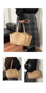 Detailed view of cream tote bag with wave-cut edge and metal M pendant accessory