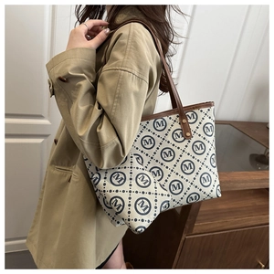 Detail of elegant patterned tote bag with brown straps and rivets for commuter fashion