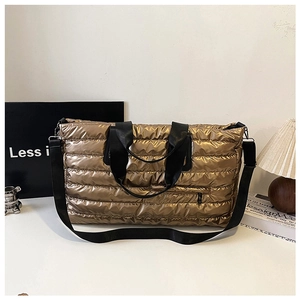 Vue détaillée du tissu matelassé métallisé bronze et du zip avant du grand sac de voyage