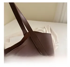 Close-up of brown leather tote bag showing high-density stitching and reinforced strap