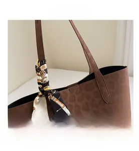 Detail of leopard print faux suede tote bag featuring a decorative silk handle scarf