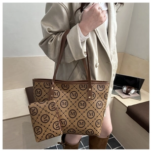 Detail of monogram tote bag set with matching pouch worn by model in a minimalist room