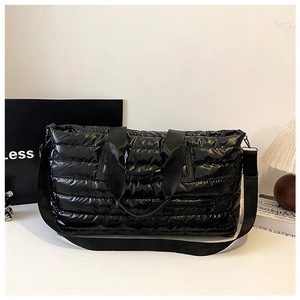 Détail du sac de voyage matelassé noir avec bandoulière large et poignées en tissu noir
