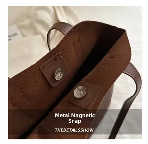 Detailed close-up of the magnetic snap closure on a premium brown leather tote bag