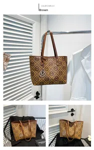 Détail d'un sac cabas marron avec motif monogramme M et pendentif argenté chic
