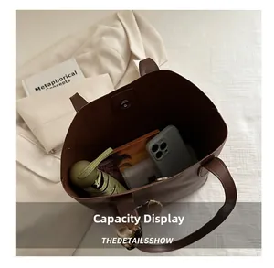 Internal view of brown tote bag showing large capacity with phone, umbrella and notebook