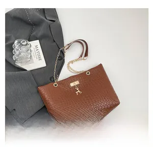 Detail of brown woven tote bag featuring gold deer charm and chain shoulder strap