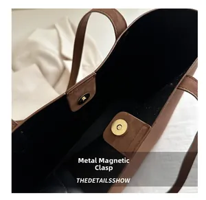 Macro view of gold magnetic closure on brown pebble leather tote bag with black lining