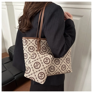 Detail of a chic cream and brown monogram tote bag with matching pouch on a model