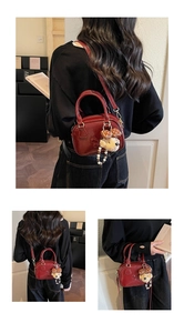 Deep red mini bowling bag featuring horse embossing and plush bear charm on model
