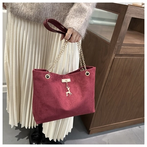 Close-up of burgundy frosted leather tote featuring gold chain and deer pendant