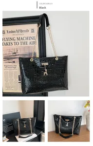 Detail of black crocodile texture tote bag with gold deer pendant and chain strap