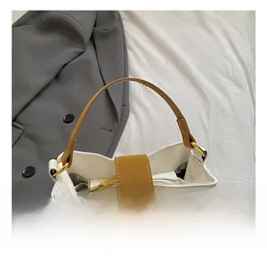 Detail of white leather bucket bag with brown handles and elegant gold hardware clasp