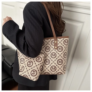 Detail of printed canvas tote bag with brown leather trim and matching inner pouch