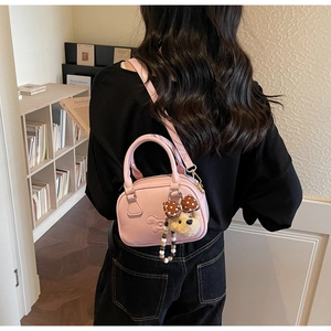 Pink small bowling bag with embossed puppy pattern and plush charm shown on model