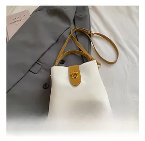 Two-tone bucket bag detail with yellow leather strap and golden twist lock on grey blazer