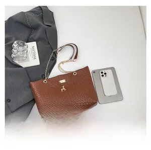 Detail of woven brown tote bag with gold deer charm and chain strap next to a grey blazer
