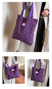 Close-up of a purple quilted tote bag featuring a colorful floral pattern and woven handles