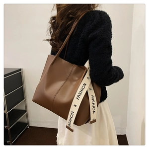 Rear view of model wearing a large brown PU leather tote bag with fashion strap