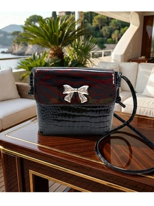 Detail of luxury crocodile texture shoulder bag with zebra print flap and silver bow clasp