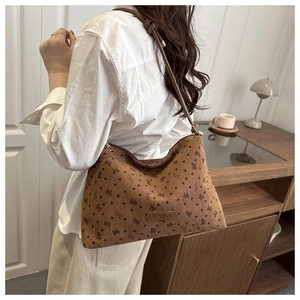Detailed texture of brown corduroy hobo bag with heart and bow patterns on a shoulder strap