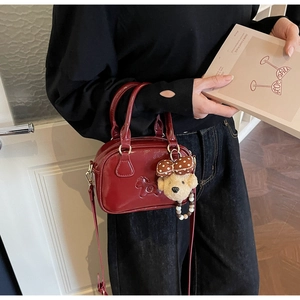 Close-up of wine red patent leather bowling bag with teddy bear charm and gold hardware